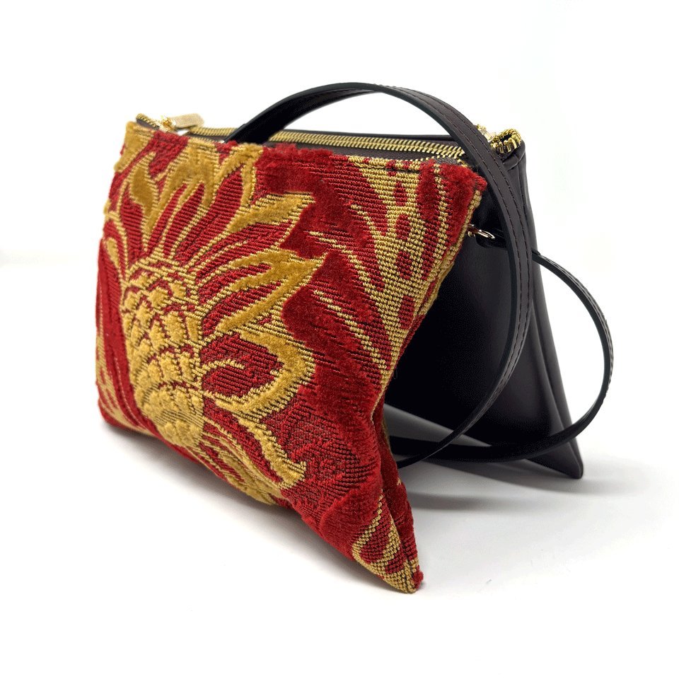 A pouch in red velvet with a gold flower woven through it, beside its dark second half