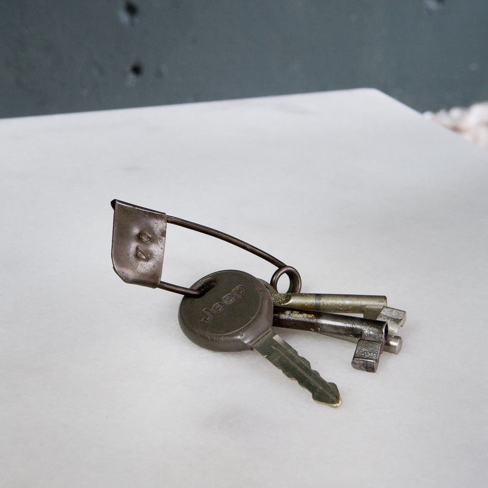 An XL safety pin standing in for a keyring, a bunch of worn keys on it.
