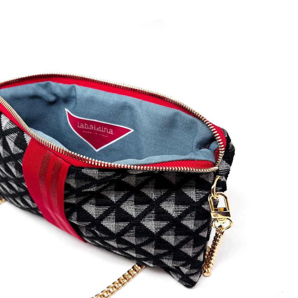 The open pochette showing the grey and black diamond, pale blue lining and a small red label at the seam