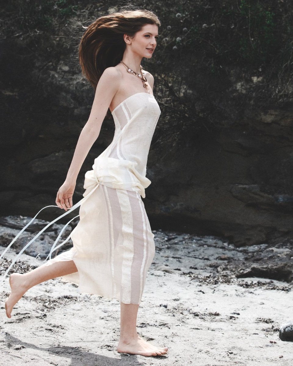 A woman in a pale strapless dress, caught mid stride on the sand