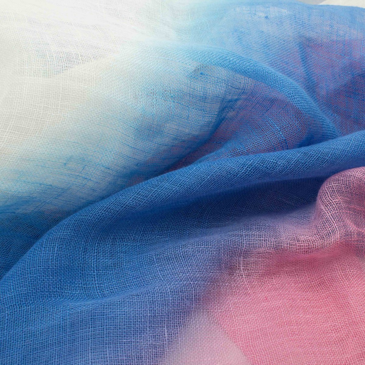 Draped linen in soft folds, its open weave shading through cream, blue and pink