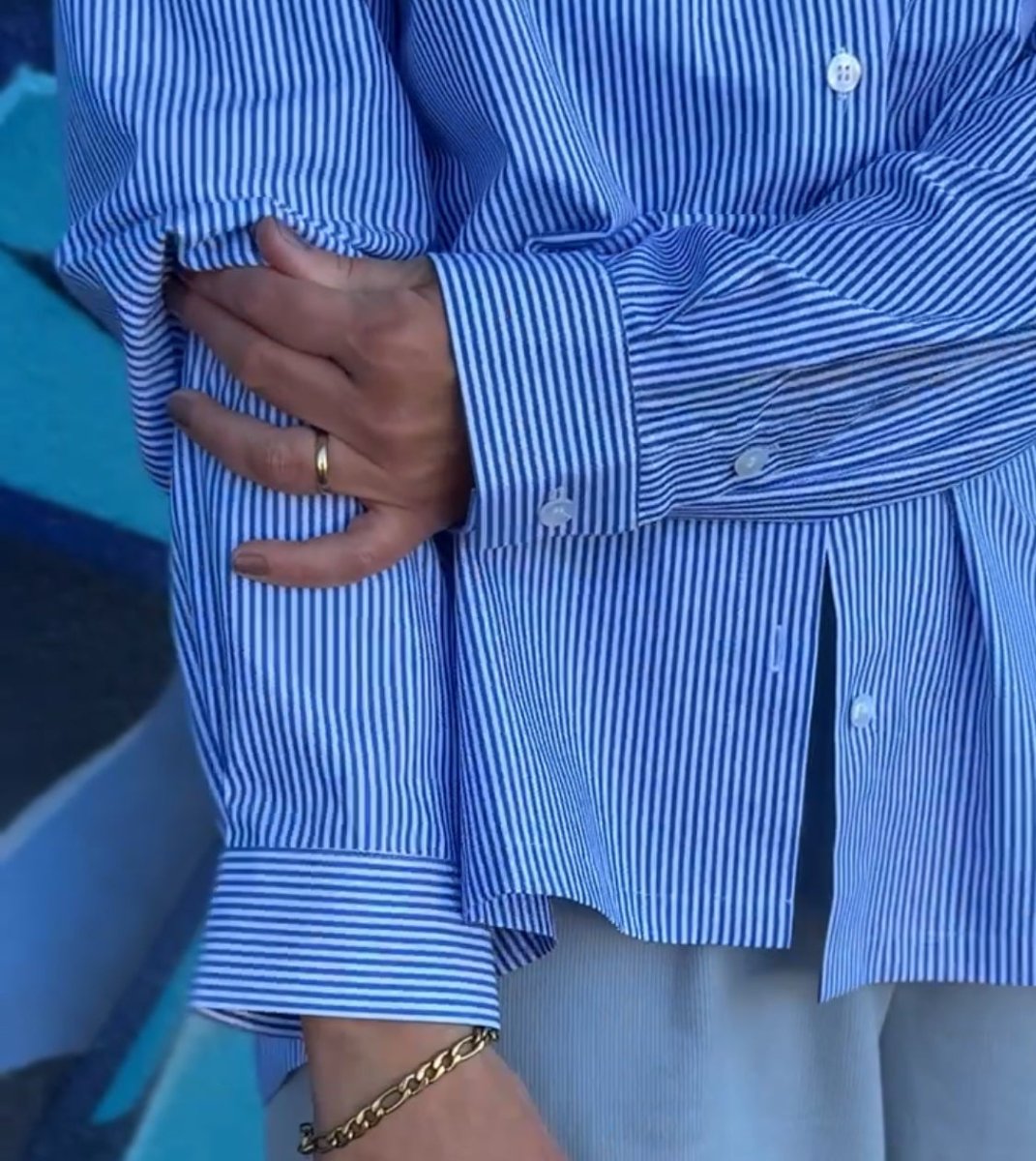 A sleeve cuff close up, pleat and stitching in focus, one ringed hand