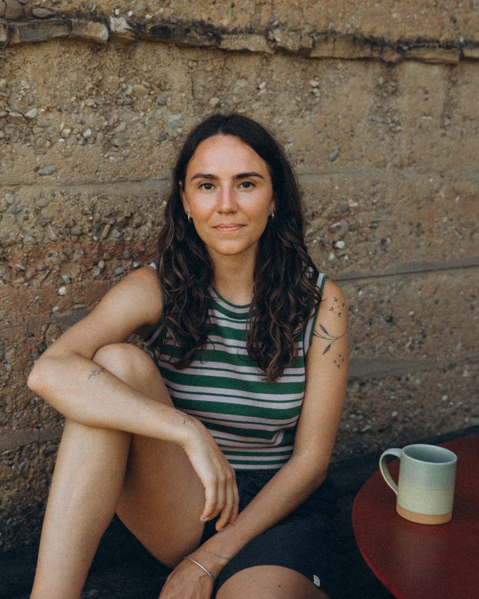 A striped knit top in organic cotton, worn plainly against a concrete wall.