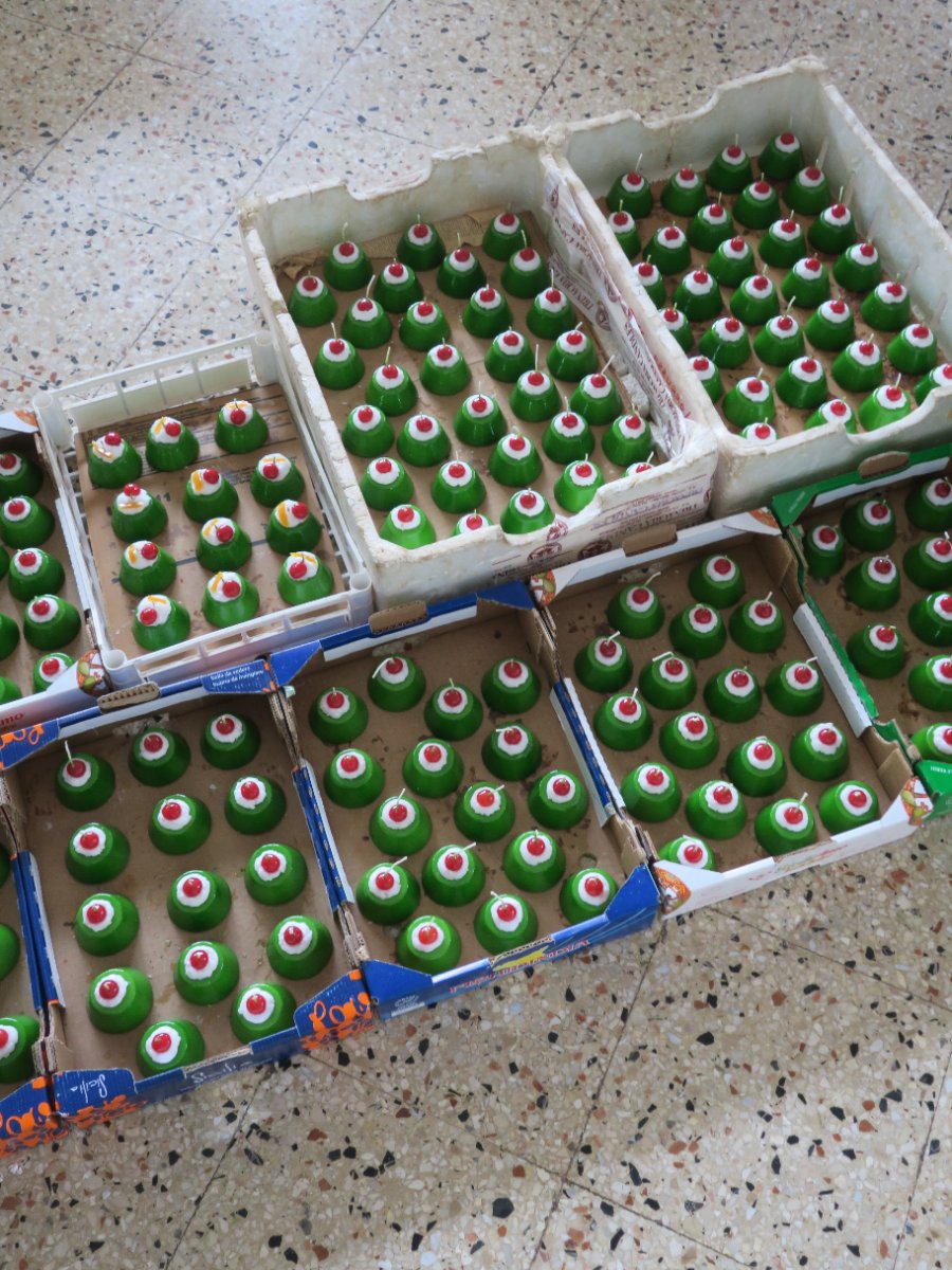 Cardboard trays of green cupcake candles on a terrazzo floor at the candle manufactory