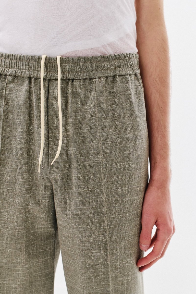 The waistband pulls with a drawstring, and the crease runs down the leg.