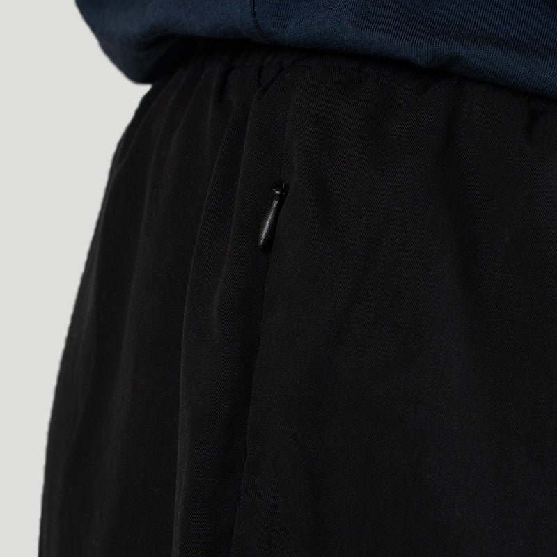 The hip of the shorts, worn, with the small zip pull set flat into the pocket seam.