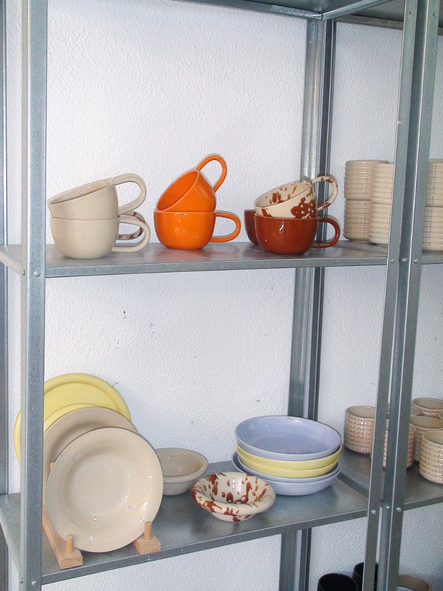 Finished cups, plates and bowls on the studio shelf.