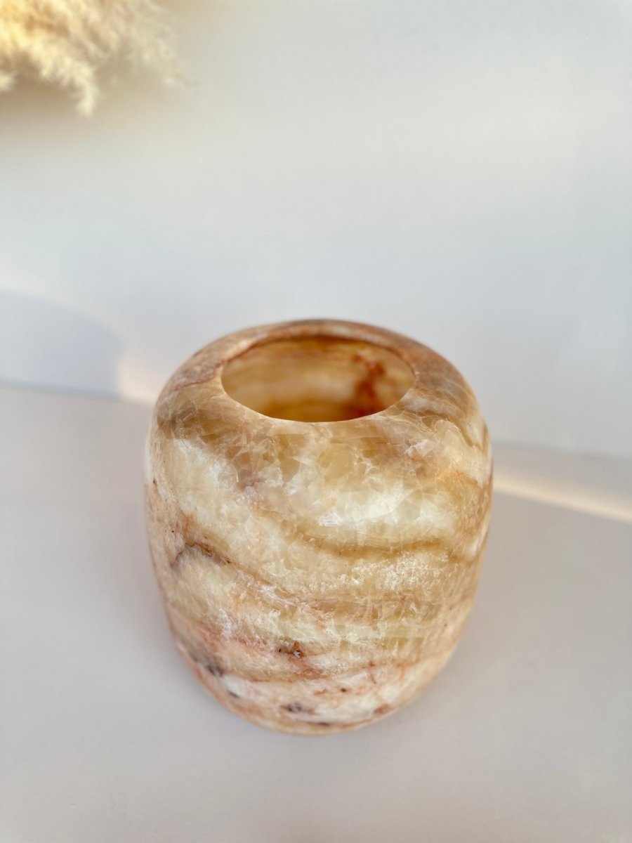A single candle holder, hollowed out, its amber and cream bands running round the stone