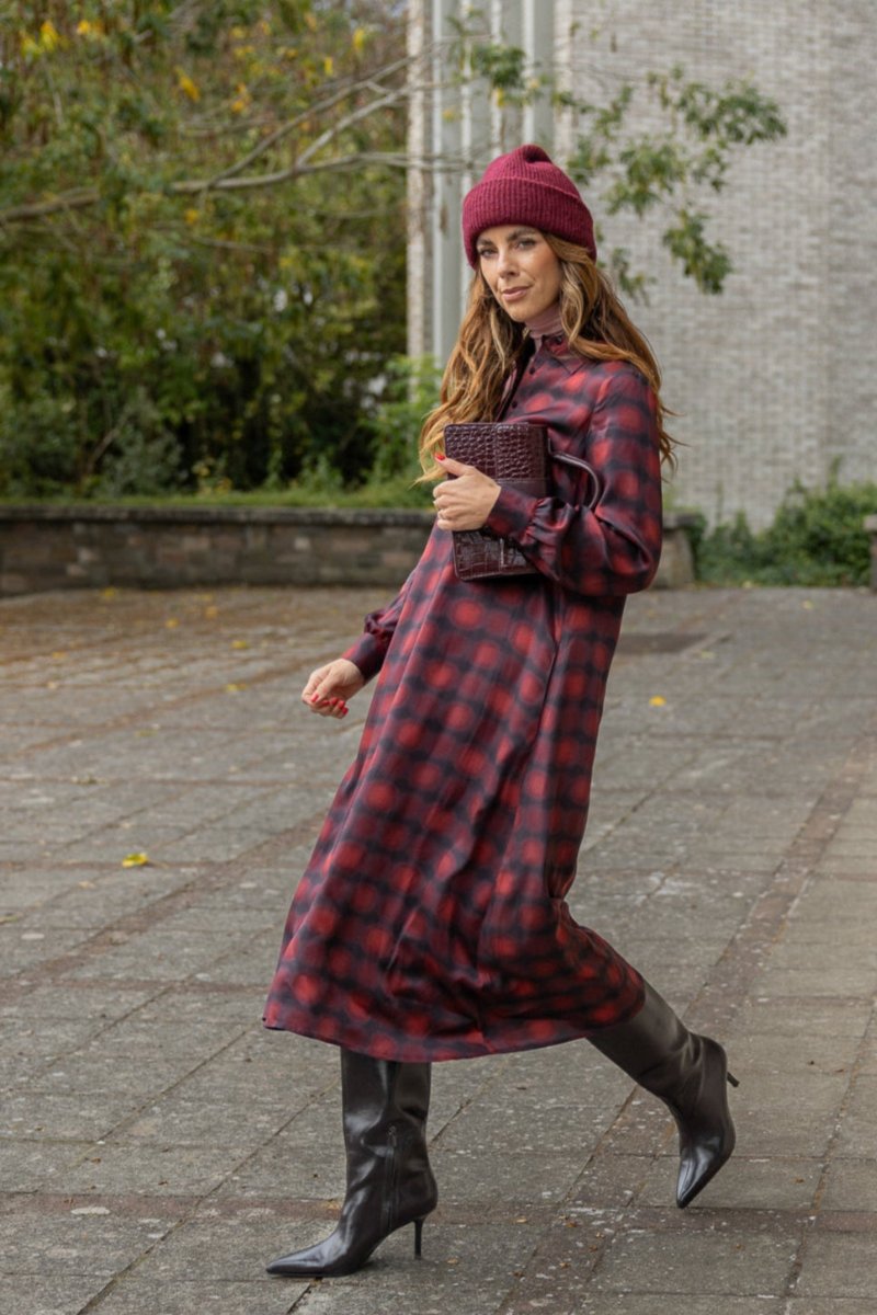 A dark red checked shirtdress and a beret on a cobbled street