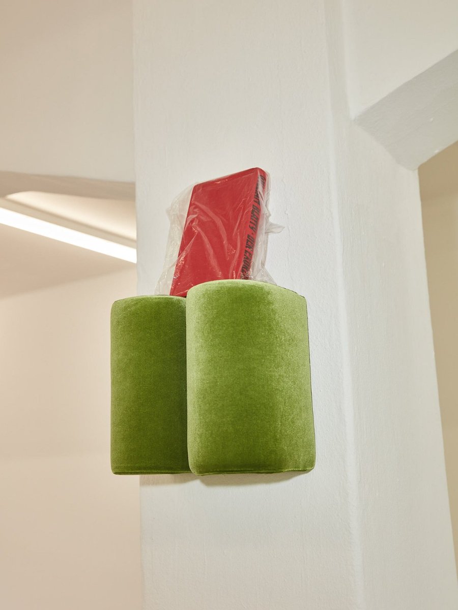 Two velvet Hold On hooks on the wall, a red packet resting on top