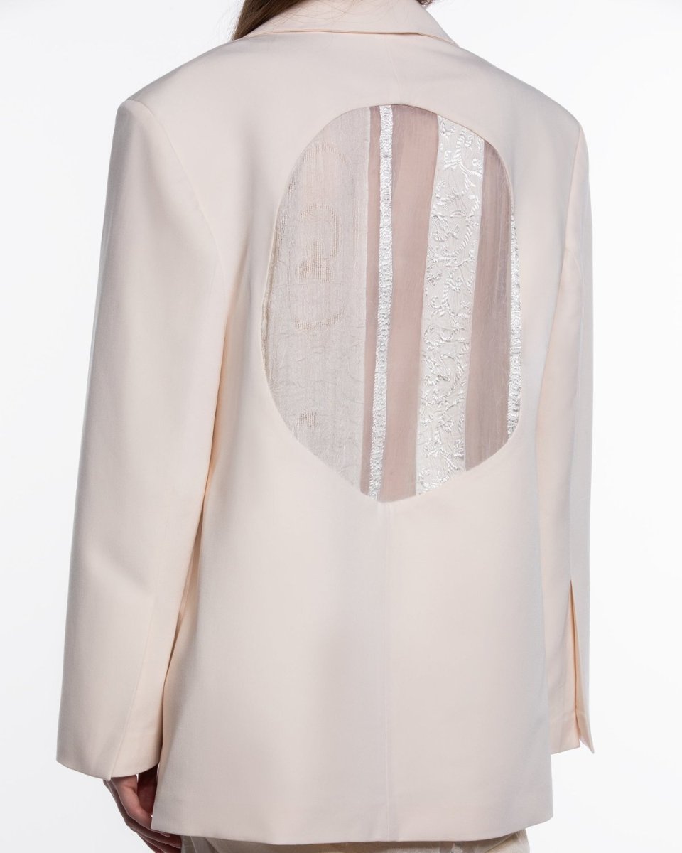 The back of a cream jacket, an oval inset of sheer woven fabric
